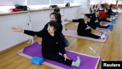 A teacher coaches an elderly person during a yoga class at Mama Sunset, a learning center for middle-aged and senior people in Beijing, China, Jan. 15, 2024.