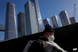 一名打工人扛着他的行李行走在北京商务区。（2023年3月15日）