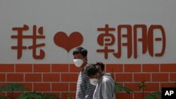 北京朝阳区两个带着口罩的居民去排队做新冠核酸检测。（2022年5月11日）