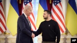 Presiden Ukraina Volodymyr Zelenskyy, kanan, dan Presiden AS Joe Biden berjabat tangan saat pertemuan mereka di Kyiv, Ukraina pada 2023. (Foto: via AP)