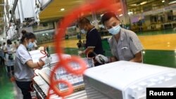中国湖北武汉格力厂的工人在制作空调机的生产线上工作。（2021年8月9日）